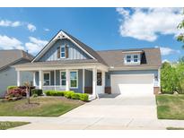 Charming blue home featuring a welcoming front porch, two-car garage, and beautifully landscaped yard at 1208 Steinbeck Dr, Durham, NC 27703