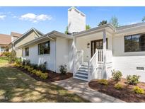 Charming white brick home featuring a classic front porch, landscaped garden, and inviting entrance at 1310 Mayfair Rd, Raleigh, NC 27608