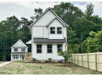 Two-story home boasts white siding, black metal roof accents, and a newly installed wooden fence at 1448A Maplewood Dr, Durham, NC 27704