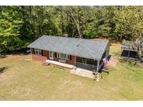 Charming brick home with a screened-in porch, bench, and an American flag in a wooded setting at 19461 Nc Highway 210, Angier, NC 27501