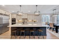 Spacious kitchen with a large island, pendant lighting, stainless steel appliances and wooden bar stools at 2437 Terri Creek Dr, Fuquay Varina, NC 27526