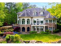 Stunning back exterior featuring a stone patio, landscaped garden, and an expansive deck overlooking a lush backyard at 25303 Ludwell, Chapel Hill, NC 27517