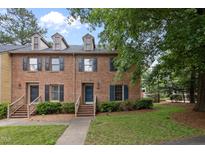Charming brick townhome with dormer windows, a quaint entrance, and lush green landscaping at 3100 Coachmans Way, Durham, NC 27705