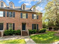 Charming brick townhome featuring dormer windows, black shutters, and a well-manicured front yard at 3100 Coachmans Way, Durham, NC 27705