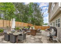 A large patio area has a dining table, cushioned chairs, and a wooden privacy fence at 406 Sapphire Dr, Durham, NC 27703