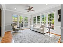 Sun-filled living room featuring a comfortable couch, accent chair, and large windows overlooking the backyard at 4513 Touchstone Forest Rd, Raleigh, NC 27612