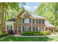 Charming brick home with black shutters, lush landscaping and a manicured lawn on a sunny day at 5912 Weather Rock Ct, Raleigh, NC 27613