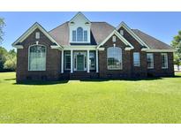 Attractive brick home featuring a manicured lawn, arched windows, and a covered entryway with classic columns at 84 Dogeye Rd, Benson, NC 27504