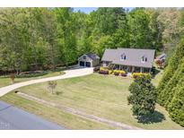 An aerial view of a charming home with a large front lawn, a detached garage, and surrounded by lush trees at 936 Elbridge Dr, Raleigh, NC 27603