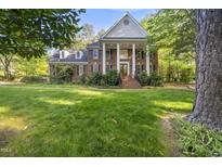 Stately brick home with white columns, lush lawn, and mature trees creating a picturesque setting at 104 Arcadia Ln, Chapel Hill, NC 27514