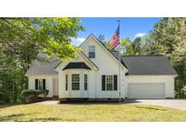 Charming white home featuring an American flag, bay window, manicured lawn, and attached garage at 105 Coral Ridge Cir, Franklinton, NC 27525
