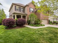 Charming brick home featuring mature landscaping, a welcoming front porch, and an attached two-car garage at 111 Gathering Place Pl, Durham, NC 27713