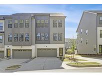 Modern gray townhome featuring a two car garage, gray siding, and a well manicured lawn at 1215 Corkery Ridge Ct, Cary, NC 27519