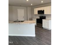 Modern kitchen featuring white cabinets, stainless steel appliances, and a marble countertop island at 147 Landon Pl, Roxboro, NC 27573