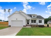 Charming, new construction one-story home with white siding, black accents, and a well-manicured front yard at 203 Sourgum Ct, Zebulon, NC 27597