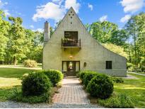 Charming home with unique architecture, front balcony, brick path and mature landscaping, and an inviting entrance at 2509 Nc 57, Hillsborough, NC 27278