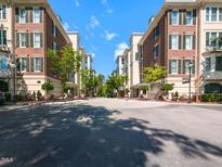 Beautiful street view showcasing well-maintained brick townhomes with lush green trees and inviting landscaping at 2813 Market Bridge Ln # 204, Raleigh, NC 27608