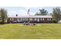 Charming brick ranch with manicured lawn, American flag, and butterfly garden at 481 Firetower Rd, Louisburg, NC 27549
