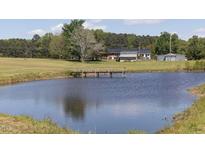 Scenic view of a tranquil pond with a wooden bridge leading to a charming country home in the background at 481 Firetower Rd, Louisburg, NC 27549