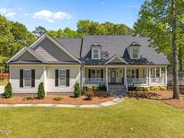 Inviting home with a charming front porch and manicured lawn and neutral color palette at 6907 Field Hill Rd, Raleigh, NC 27603