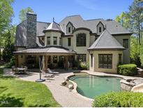 Expansive backyard featuring an in-ground pool, stone patio, fireplace, and lush landscaping at 1009 Linenhall Way, Wake Forest, NC 27587