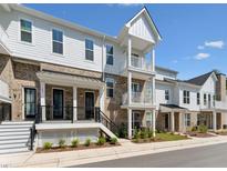 A beautiful exterior view of a modern brick and white townhouse with a cozy porch and balcony at 11549 Helmond Way # 103, Raleigh, NC 27617