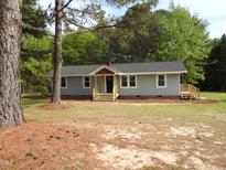 Charming single-story home with light blue siding, a dark roof, and a welcoming front porch and manicured lawn at 1165 John Mitchell Rd, Youngsville, NC 27596
