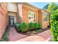 Charming brick home featuring a beautiful black iron gate, manicured shrubs, and a well-maintained brick walkway at 12 Innisfree Dr, Durham, NC 27707