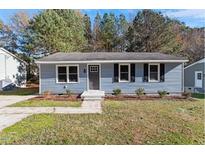Charming single-story home with blue siding, black shutters, and well-maintained front yard landscaping at 1203 Freeman Dr, Sanford, NC 27330