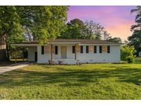 Charming single-story home with white brick and black shutters, complemented by a well-maintained lawn at 124 Strickland Dr, Smithfield, NC 27577