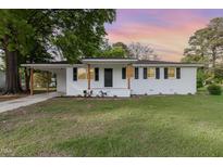 Charming white brick home featuring black shutters, wood columns, a covered carport and a well-maintained front yard at 124 Strickland Dr, Smithfield, NC 27577