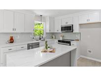 Bright kitchen features white cabinets, modern appliances, light countertops and a large window at 1514 Goodwin Rd, Durham, NC 27712