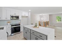 Bright kitchen features gray island, stainless steel appliances, white cabinets, and access to the living room at 1514 Goodwin Rd, Durham, NC 27712
