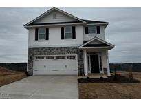 Two story home features a 2-car garage, stone accents, and neutral color palette at 177 Kipling Creek Dr, Fuquay Varina, NC 27526