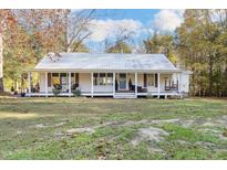 Charming single-story home with a full-width porch and a metal roof, set on a spacious lot with mature trees at 1835 Pearidge Rd, Angier, NC 27501