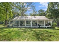 Charming single story home with a sprawling front porch, metal roof and mature trees at 1835 Pearidge Rd, Angier, NC 27501