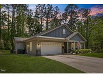 Charming one-story home with a two-car garage, manicured lawn, and inviting front porch at 205 Sacred Fire Rd, Louisburg, NC 27549