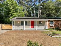 Charming home featuring a cozy front porch, red front door, solar panels, and a beautifully landscaped yard at 2506 N Duke St, Durham, NC 27704