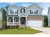 Charming two-story home with a covered front porch, stone accents, manicured lawn, and two-car garage at 2749 Nettles Ridge Way, Fuquay Varina, NC 27526