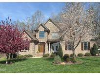 Inviting brick home featuring a well-manicured lawn and beautiful blossoming trees under a bright blue sky at 4103 Cheek Point Pl, Burlington, NC 27215