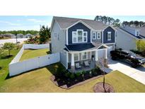 Charming two-story home featuring a welcoming front porch and well-manicured lawn, enclosed by a white fence at 490 Mallard Loop Dr Dr, Clayton, NC 27527