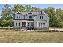 Beautiful two-story home featuring a manicured lawn and a symmetrical facade and covered porch at 67 Farmstead Ct, Wendell, NC 27591