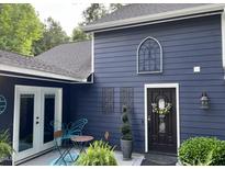 Charming front exterior with dark siding, decorative windows, front door with wreath, and stylish outdoor furniture at 6765 Rock Service Station Rd Rd, Raleigh, NC 27603