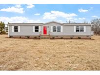 Charming single-story home featuring gray siding, a bright red front door, and well-manicured landscaping at 7289 Nc 561, Louisburg, NC 27549
