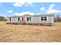 Charming single-story home featuring vinyl siding, white trim and a bright red front door at 7289 Nc 561, Louisburg, NC 27549