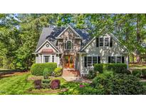 Charming stone front home with mature landscaping, manicured lawn, and arched window at 5113 Windance Pl, Holly Springs, NC 27540