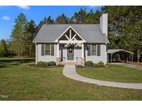 Charming one-story home with a metal roof, gray siding, and a welcoming walkway, plus covered parking on a lush, green lot at 108 Ruff Davis Rd, Roxboro, NC 27574