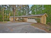 Charming brick ranch-style home with attached garage and circular driveway nestled among mature trees at 110 Omega Rd, Henderson, NC 27536