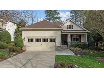 Charming home exterior features a manicured lawn, stone accents, a two car garage, and a cozy front porch at 1320 Heritage Hills Way, Wake Forest, NC 27587