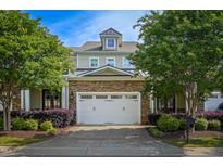 Charming townhome featuring a two-car garage, stone accents, and landscaped front yard for added curb appeal at 2307 Carriage Oaks Dr, Raleigh, NC 27614